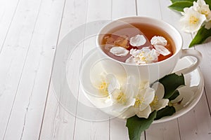 Mug of herbal tea with petals of Jasmine flowers on a light background