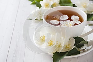 Mug of herbal tea with petals of Jasmine flowers on a light background. Copy space