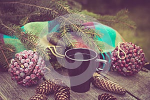 Mug of hot beverage on a rustic wooden table. Still life of cones, twine, packthread, fir branches. Preparing for Christmas.