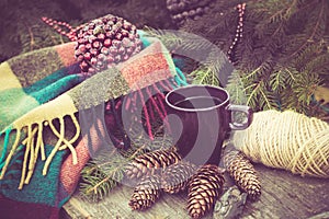 Mug of hot beverage on a rustic wooden table. Still life of cones, twine, packthread, fir branches. Preparing for Christmas.