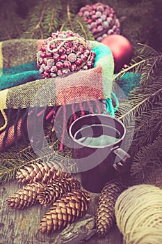 Mug of hot beverage on a rustic wooden table. Still life of cones, twine, packthread, fir branches. Preparing for Christmas.