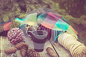 Mug of hot beverage on a rustic wooden table. Still life of cones, twine, packthread, fir branches. Preparing for Christmas.