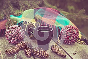 Mug of hot beverage on a rustic wooden table. Still life of cones, twine, packthread, fir branches. Preparing for Christmas.