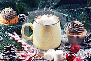 Mug with hot chocolate and cup cake snow wooden table