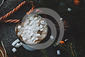 Mug of hot chocolate with marshmallow, fir branches, Lollipop, cone, Golden balls, cinnamon on a dark background, winter Christmas