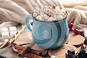 Mug of hot chocolate with marshmallow and a Lollipop on a knitted blanket background. Cozy warm winter composition