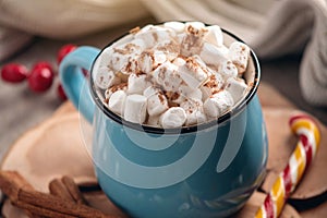 Mug of hot chocolate with marshmallow and a Lollipop stick on a knitted blanket background. Cozy warm winter composition