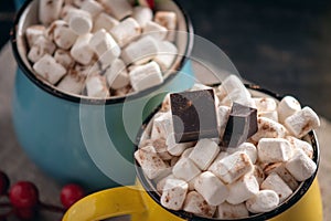 Mug of hot chocolate with marshmallow on top and Lollipop stick on dark wooden background. Cozy warm winter composition