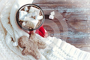 Mug of hot chocolate with marshmallows and ginger man, cookies, white sweater on a wooden background, winter hot drink