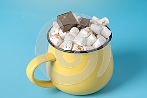 Mug of hot chocolate with marshmallows on top on a blue background. Cozy winter card