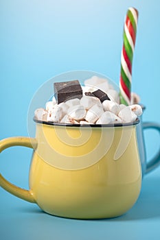 Mug of hot chocolate with marshmallows on top and stick a Lollipop on a blue background. Cozy winter card