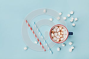 Mug of hot cocoa or chocolate and straw on turquoise table top view. Flat lay. photo