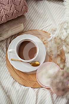 A mug of hot cocoa knitted sweaters a bouquet of white dried flowers in a vase a candle on the bed. Breakfast in bed. Cozy