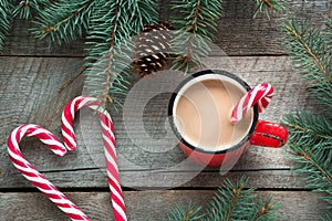 Mug hot coffee with milk, red candy cane in shape of heart on the wooden background. New Year. Holiday card. Rustic style. Top vie