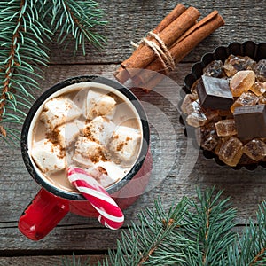Cup of hot coffee with milk, red candy cane on the wooden background. New Year. Holiday card. Rustic style. Top view.