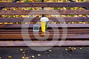 Mug of hot tea and coffee, standing on park bench, white telfon the spring autumn weather, the concept the idea
