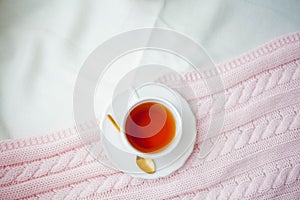 A mug of hot tea  a knitted pink plaid on the bed. Breakfast in bed. Cozy