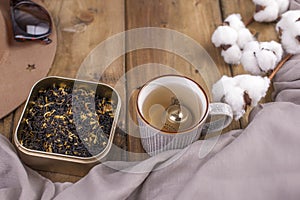 A mug of hot tea on a wooden background and a scarf. Autumn and winter accessories in a frame composition. Top view. Free space.