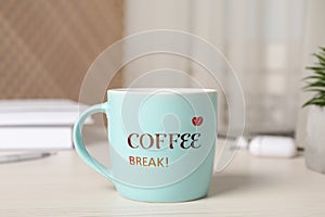 Mug with inscription Coffee Break on white wooden table in office