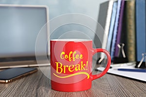 Mug with inscription Coffee Break on wooden table in office