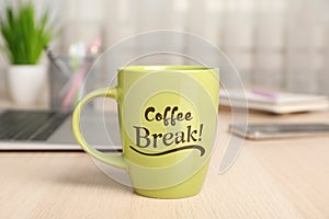 Mug with inscription Coffee Break on wooden table in office