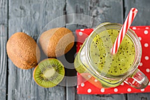 A mug with a kiwi smoothie and a bowl with kiwi slices on a rustic wooden table. The view from the top.