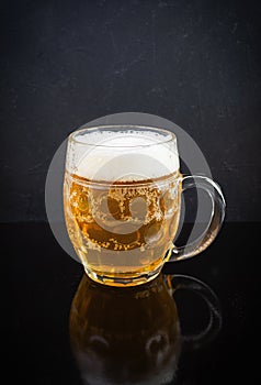 Mug of light beer on dark background. Craft unfiltered beer