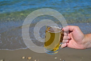 A mug of light beer in the hand of a man.