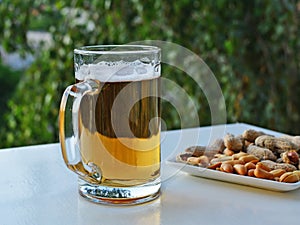Mug of light beer and peanuts on the table