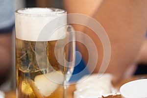 Mug of light beer pills with foam on a wooden table