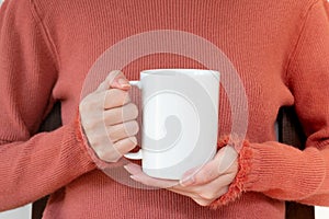 Mug mockup. Women`s hands holding mug with blank space for your text or promotional content