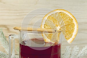 Mug with mulled wine, cinnamon and lemon on wooden background