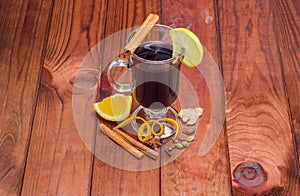 Mug of mulled wine and mulling spices on wooden surface