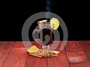 Mug of mulled wine and mulling spices on wooden surface