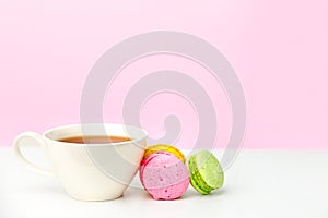 Mug on the table and colored biscuits on a white wooden table