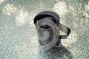 Mug of tea or coffee standing on the silver colored metallic background