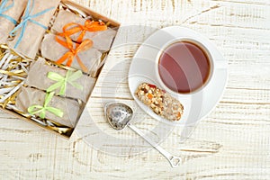 Mug of tea, muesli bars and tea strainer. Box with bars. White w