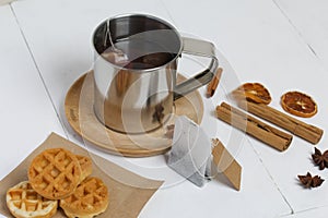 Mug of tea and waffles. Nearby are cinnamon, anise and dried oranges on the table. Autumn still life