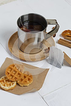 Mug of tea and waffles. Nearby are cinnamon, anise and dried oranges on the table. Autumn still life