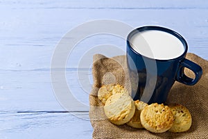 Mug of warm milk and cookies before bed. Blue cup with fresh milk and tasty cookies.