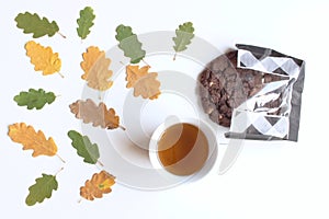 Mug with warm tea and cookies,fallen autumn leaves on white wooden table .Top view. Autumn, cozy composition