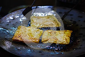 Mughlai paratha, an indian street fast food is being fried in oil in a frying pan