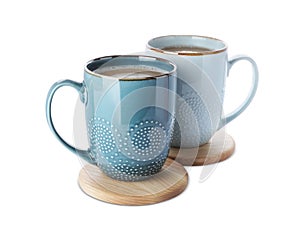 Mugs of coffee and stylish wooden cup coasters on white background