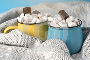 Mugs of hot chocolate with marshmallows on top on a blue background. Cozy winter card
