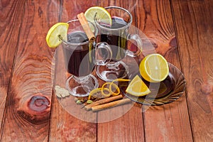 Mugs of mulled wine and mulling spices on wooden surface