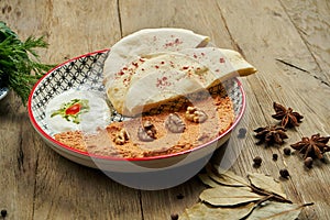 Muhammara is a classic eastren dish. baked pepper and walnut puree with Bazlama and yogurt in a ceramic plate on a wooden