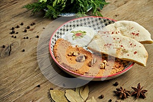 Muhammara is a classic eastren dish. baked pepper and walnut puree with Bazlama and yogurt in a ceramic plate on a wooden