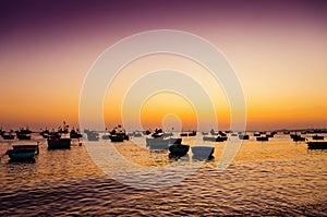 Mui Ne fishing harbour with many fishing boats in the sea during a beautiful sunset