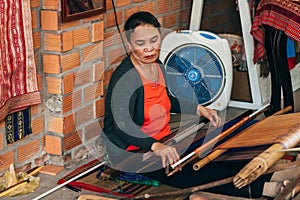 MUI NE, VIETNAM - MARCH 6, 2017: A woman weaver at a traditional loom for yarn silk