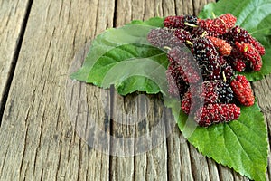 Mulberry balls on mulberry leaves, wood background